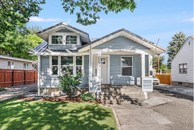 A restored blue Craftsman-style home with a front porch and landscaped yard